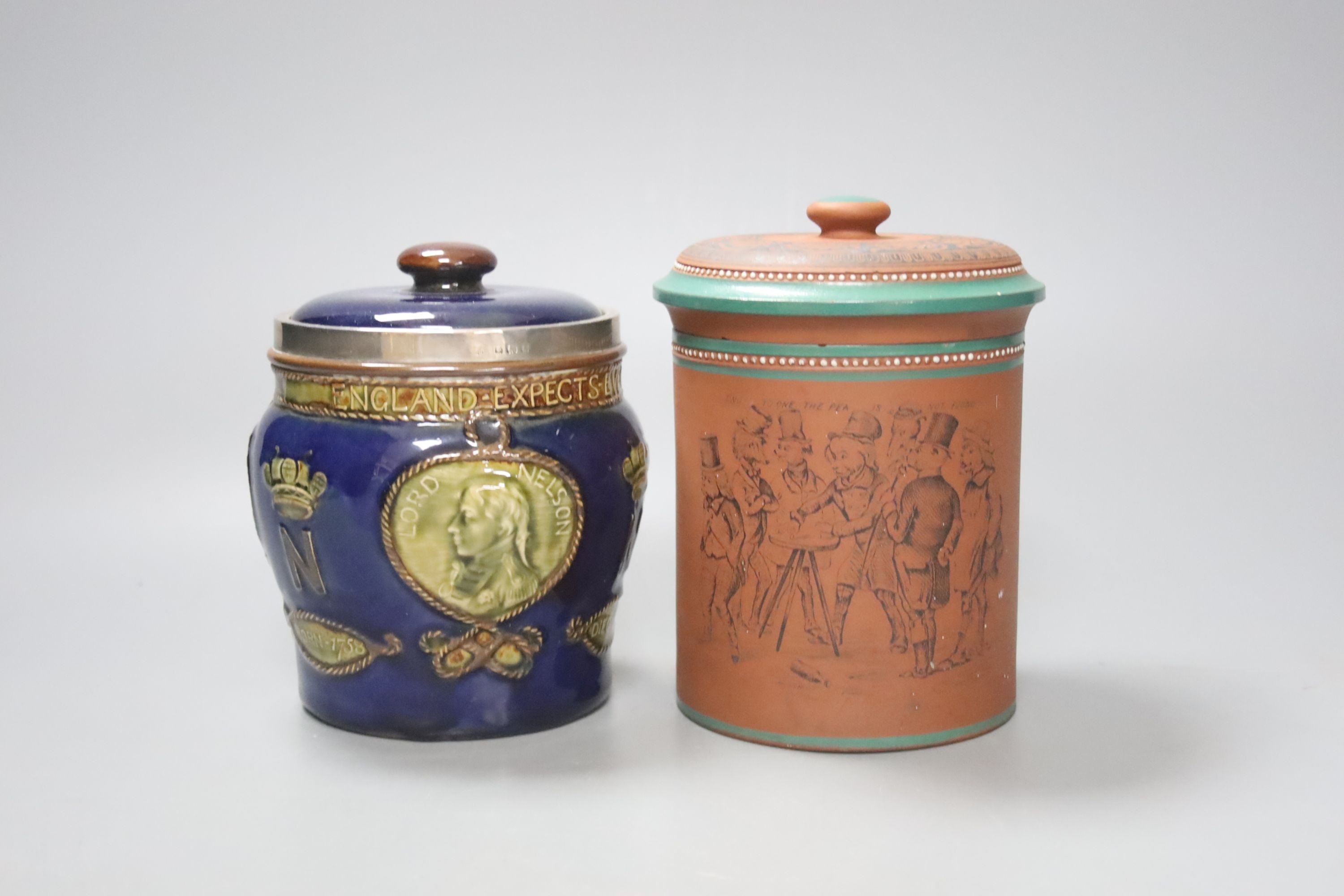 A Doulton Lambeth Nelson commemorative tobacco jar and cover 13.5 cm high, with silver mount (cracked) and a Watcombe style terracotta tobacco jar and cover (2)